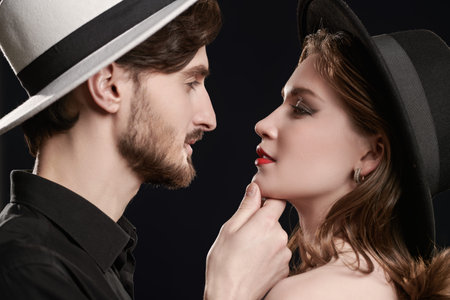 Sideview shot of a stylish young coule in elegant clothes looking into each other's eyes and...