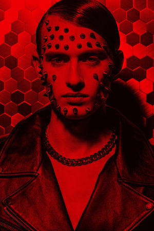 Aggressive fashion. Portrait of a brutal young man in a black leather jacket and with metal spikes...