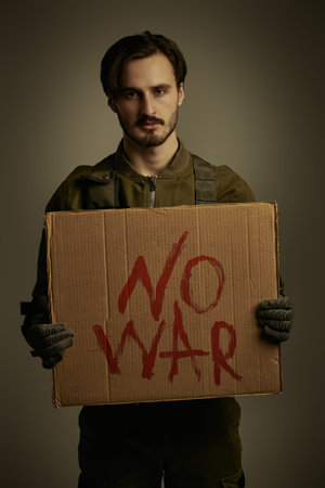 World under the threat of war. Courageous soldier in camouflage holds a sign No War in front of him....