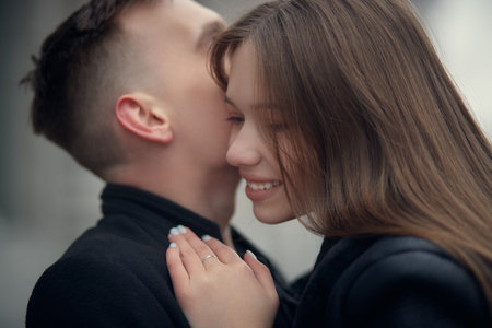 Portrait of a beautiful young people in love hugging and kissing each other standing on a city...