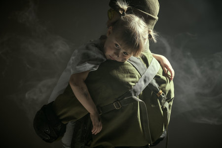 Portrait of a courageous soldier carefully carrying a little girl in his arms. Casualties of war....