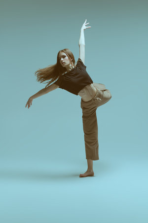 Contemporary ballet. Modern ballet dancer artistically dances on a grey background at studio. Dance...
