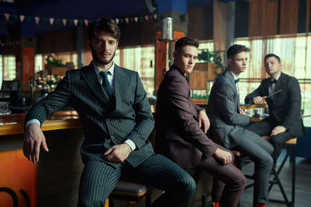 Handsome young men in stylish classic suits relax in a bar. Men's fashion. Business people club.の写真素材