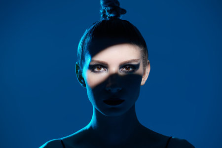 Cosmetics and makeup. Close-up portrait of a beautiful female model with dark makeup posing on a...
