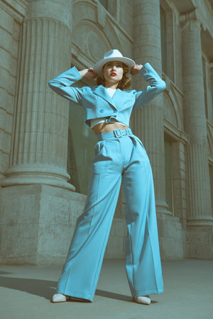 Hollywood style. Portrait of a beautiful brown-haired woman in an elegant sky blue pantsuit and a...