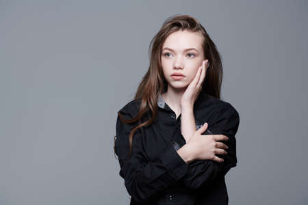 A beautiful young girl with long hair in a black shirt looking calmly away. Beauty, people, emotions. Psychological portrait.の写真素材