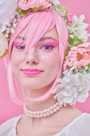 Beauty girl. Portrait of a beautiful smiling girl with bright pink makeup and pink hair with floral wreath on her head. Spring and summer beauty. Japanese anime style.の写真素材