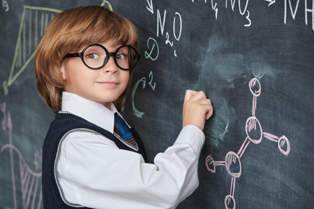 Clever kids. Education. A smart, smiling boy in neat school uniform and glasses stands at the...