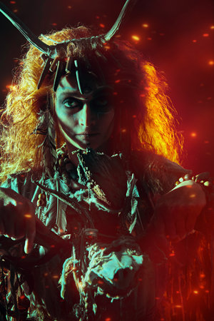 Portrait of a shaman woman in ritual clothes and deer antlers headdress posing in a dark background...