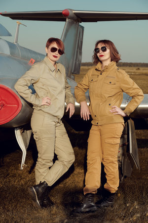 Aviation. Two professional female commercial aviation pilots in uniform and stylish sunglasses stand...