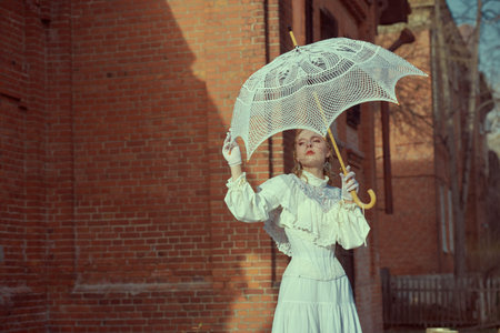 Victorian era. Vintage portrait of a beautiful aristocratic girl in a white lace dress walking...