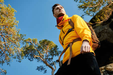 Portrait of a male hiker in special clothes and a backpack behind his back going hiking in mountains. Extreme sports, tourism. Tourist equipment. Summer vacation.の写真素材