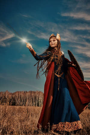 Courageous and beautiful woman warrior valkyrie fights on the battlefield with a sword and shield in her hands. Scandinavian mythology. Epic fantasy.の写真素材