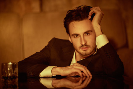 Male beauty and lifestyle. Portrait of a handsome brunet man in a luxury apartment leaning pensively...