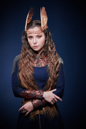 A beautiful valkyrie woman standing on a blue background. Scandinavian mythology. Fantasy.