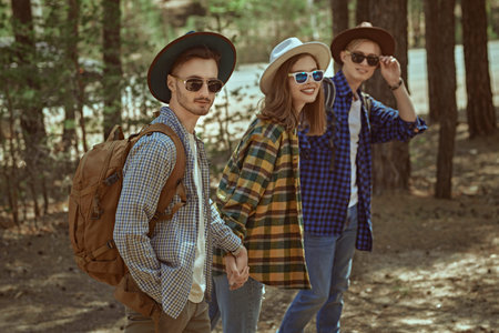 Summer vacation in nature, tourism. Cheerful young people backpackers go for a walk in a pine...