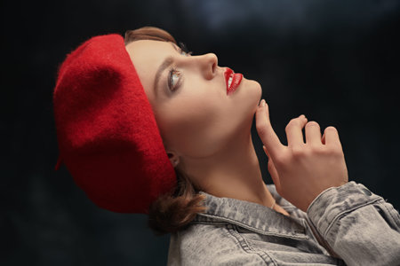 Style of the 40s. Portrait of a beautiful young woman with bright makeup in denim overalls and a red...