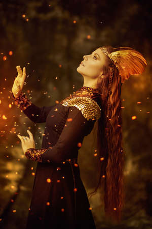 Portrait of a beautiful valkyrie woman standing in profile on a dark background with sparks of fire. Scandinavian mythology. Fantasy.の写真素材