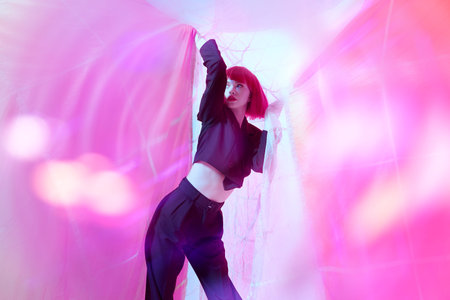 Fashion shot. Beautiful female fashion model with bright red hair poses in fashionable black...