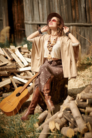 A beautiful young woman dressed in boho style clothes and jewelry enjoys the day in the countryside....