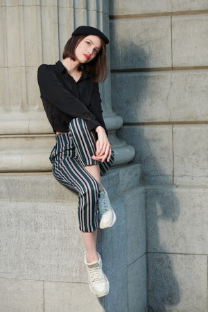 Portrait of a beautiful brunette girl with bob haircut dressed in a black blouse, black beret and...