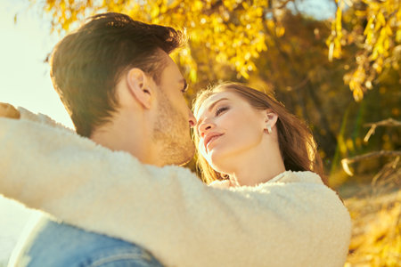 A beautiful loving couple in autumn denim clothes kissing in an autumn park on a nice sunny day....