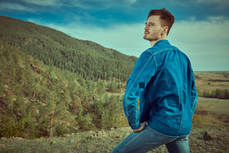Denim style and male fashion. A handsome man in denim clothes is posing against the backdrop of the...