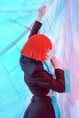Fashion shot. Beautiful female fashion model with bright red hair poses in fashionable black...