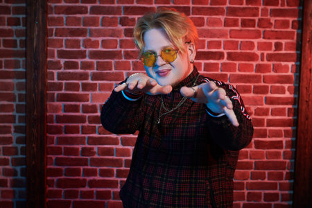 Youth culture. A modern guy with red hair and short beard wearing a casual sports suit is dancing a...
