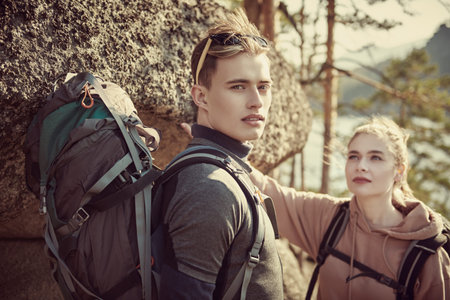 Tourism, hiking. A couple of travelers with backpacks behind their backs hike in the mountains....