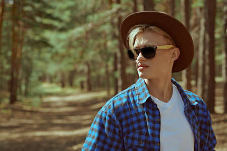 Tourism, nature exploring. Portrait of a handsome guy hiker standing on the path in a pine forest. Active rest, hiking, adventure.の写真素材