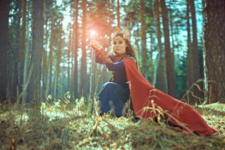 Portrait of a courageous woman warrior valkyrie in a sunny wood with a magic sword. Scandinavian mythology. Epic fantasy.の写真素材