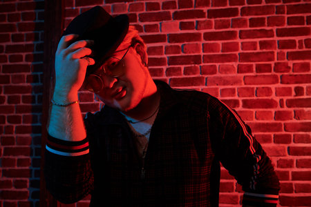 Rapper guy in a nightclub. Portrait of a plump man in modern clothes with stylish black hat and...