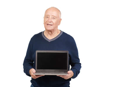 Pensioners and modern technologies. A senior man smiles holding a laptop in his hands. Studio portrait on a white background. Elderly people, lifestyle. Copy space.の写真素材