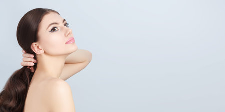 Health and beauty. Portrait of a beautiful slender girl with long brown hair and elegant makeup on a...