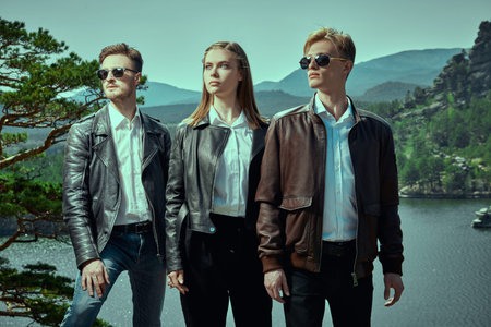 Leather clothing fashion. Portrait of three young people posing in leather jackets and classic white...
