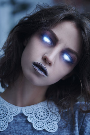 Portrait of an angry ghost girl with evil shining in the dark eyes and black hair staring intently at the camera. Horror film, thriller. Halloween.の写真素材
