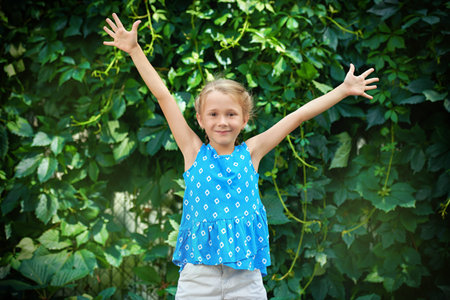 A happy girl in casual summer clothes enjoys a sunny summer day standing outside on the background...