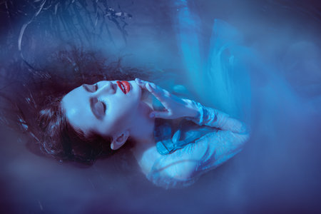 A bewitching water nymph lies in the water in the moonlight, surrounded by light mysterious haze. Fantasy. Fabulous myths and legends.の写真素材