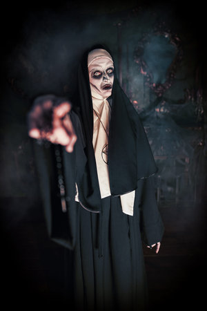 Halloween. Portrait of a cursed nun extending her hand forward, standing in the abandoned chapel....