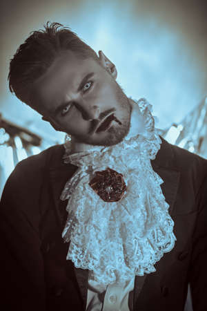 Portrait of a handsome vampire man with blood on his lips in an elegant 19th century suit. Vampires. Halloween.の写真素材