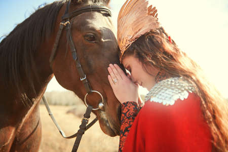 Fantasy. A beautiful valkyrie is talking to her horse standing on the battlefield. Scandinavian mythology.の写真素材
