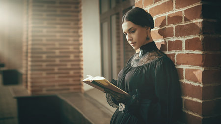 Portrait of a beautiful sophisticated girl in a strict black dress and with black, pulled back hair,...