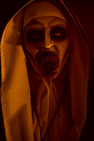 Halloween and Horrors. Portrait of a terrible cursed nun in the light of hellfire.の写真素材