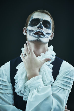 Dia de los muertos. Day of The Dead. Halloween. Portrait of a devilish handsome man with skull makeup on a black background.の写真素材