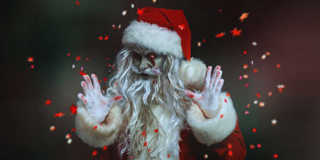 Portrait of a scary zombie Santa Claus with a bloody beard and a burning eye, who looks into the camera and laughs evilly. Black background with festive confetti. Christmas, New Year and Halloween.の写真素材