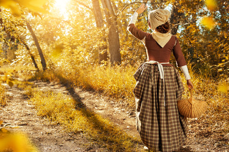 Portrait of a girl walking in a sunny summer forest with a basket of flowers. Rural Scottish girl of...
