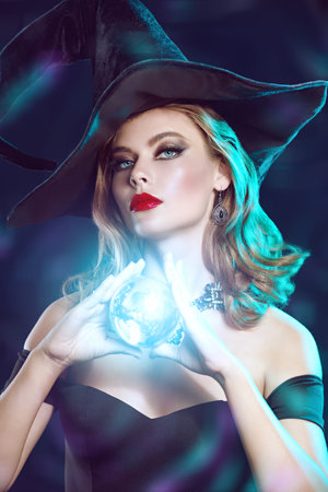 Magic on Halloween. Attractive young witch in a black hat and off-the-shoulder black dress with...