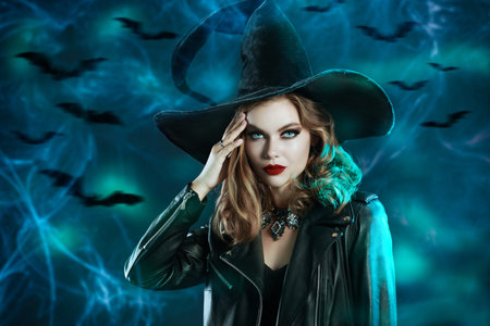 Halloween. Portrait of a pretty girl in a witch's hat and a black leather jacket standing on a dark...