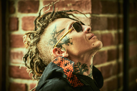 Profile portrait of a  mature brutal man with ethnic tattoos on his head and neck and with...